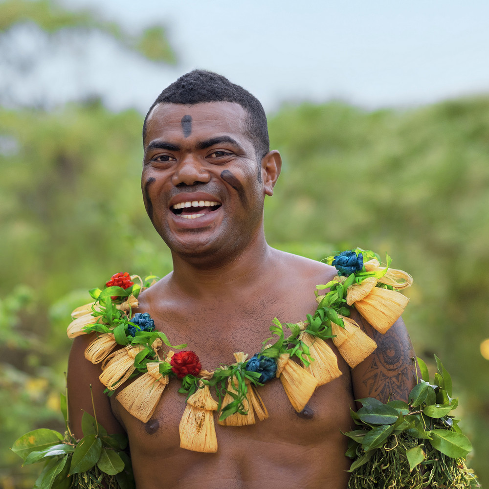 Fijian man smiling in cultural clothing.
